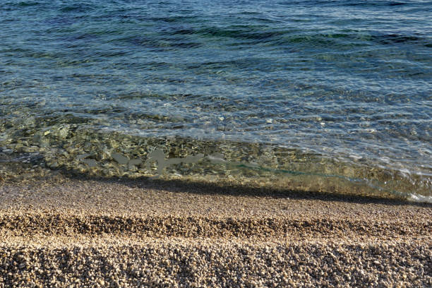 Blue sea surface and hitting waves flooded pebble beach