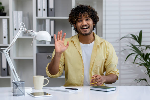 istock Smiling man waving hello at desk in modern home office environment 2162589405