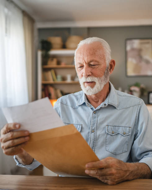istock Senior man open and read a letter document from envelope good news 2162589504