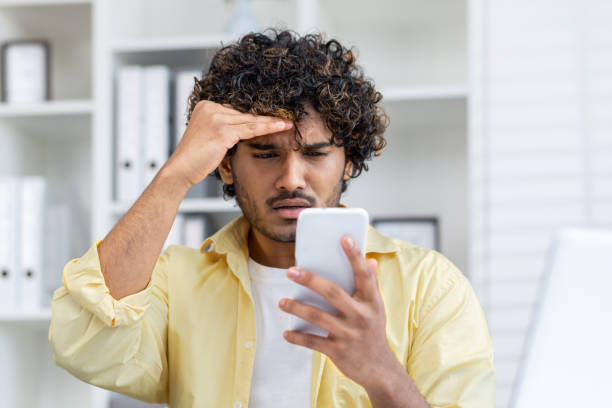 istock Frustrated young man looking at smartphone with concern in home office 2162589534