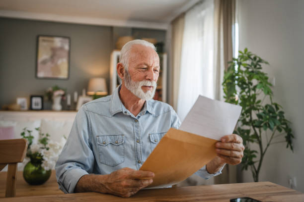 istock Senior man open and read a letter document from envelope good news 2162589551