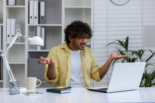 istock Frustrated man working on laptop at office desk with confused expression 2162589618