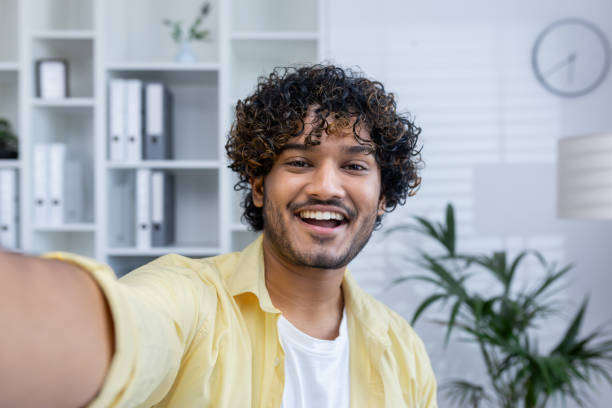 istock Happy young man taking a selfie in a modern office setting 2162590572