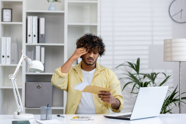 istock Young man receiving bad news while reading mail envelope in home office 2162590985