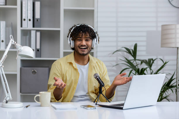 istock Smiling man hosting podcast at home office with microphone and laptop 2162591226