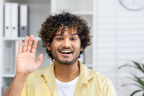istock Smiling young man waving during a video call at home office 2162592088
