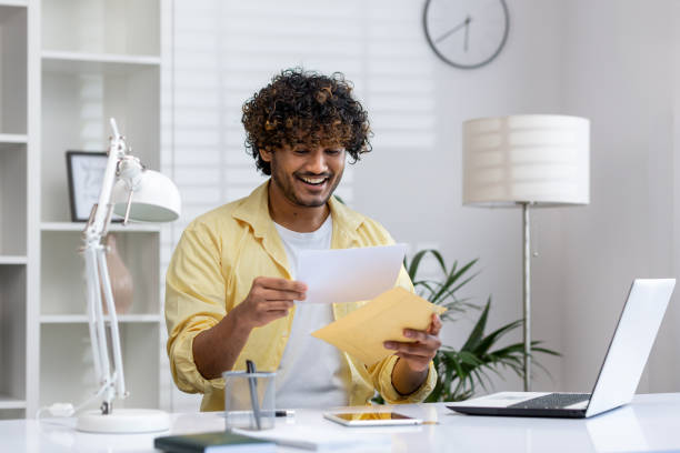 istock Happy man opening a letter in a modern office with laptop and documents 2162592202