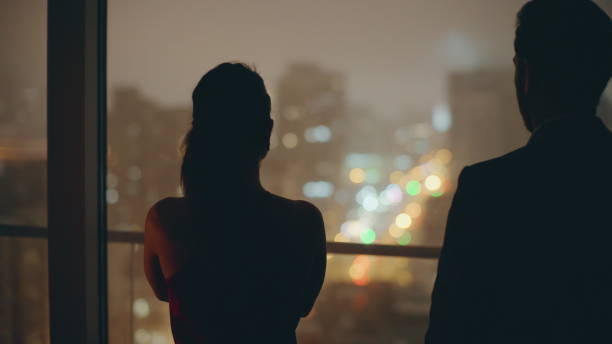 istock Romantic pair silhouettes embracing at evening window cityscape hotel back view 2162592743