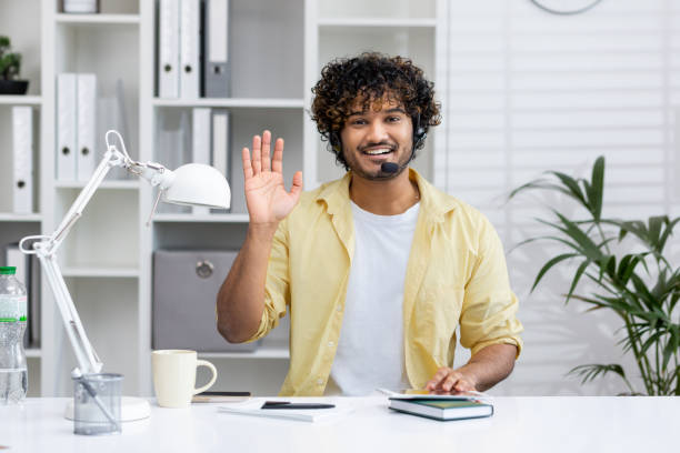 istock Young man working in a modern office wearing a headset and waving hello 2162593608