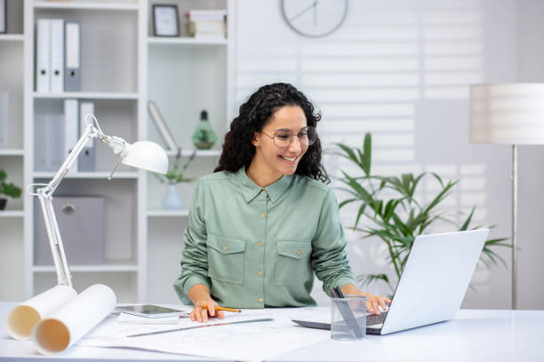 istock Hispanic woman working on architectural project on laptop in modern office 2162594294