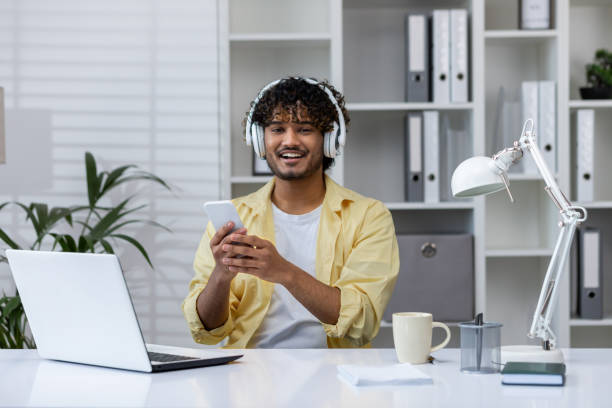 istock Man using smartphone while listening to music at modern home office desk 2162594308