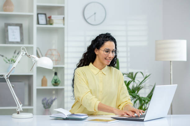 istock Smiling Hispanic woman working on laptop in a modern home office setup 2162594473