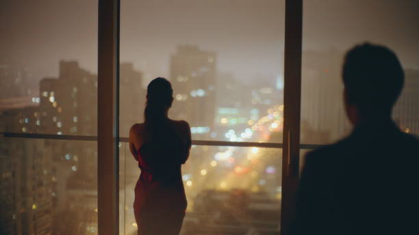istock Silhouettes romantic couple embracing at evening window cityscape back view 2162596522
