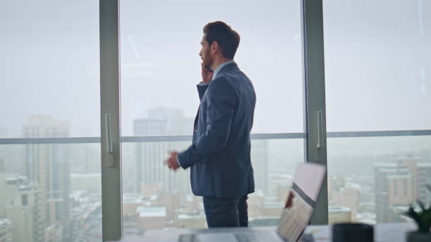 istock Businessman talking phone call negotiations standing at office panoramic window 2162596871