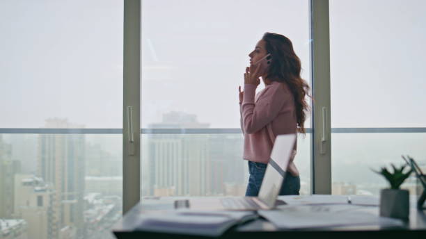 istock Serious manager having call holding cellphone near panoramic window at office 2162604351