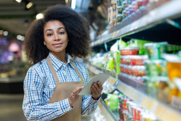 istock Grocery store employee using a tablet while working in an aisle of a supermarket 2162604376