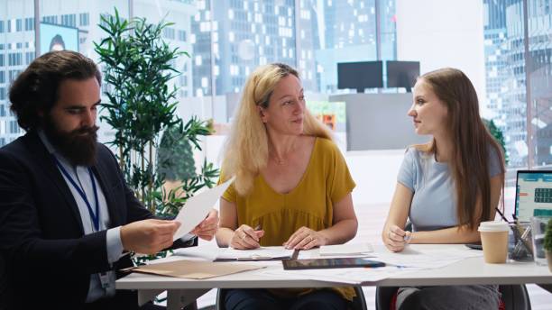 istock Financial advisor inviting clients to sign formal agreement documents 2162605800