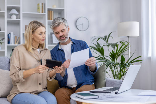 istock Mature couple reviewing documents and using a tablet at home 2162605943