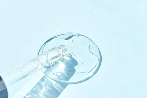 istock Serum gel texture swatch. Transparent drop golden sparkles. Blue background 2162606590