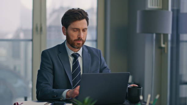 istock Serious businessman texting laptop making coffee sip panoramic workplace closeup 2162606736