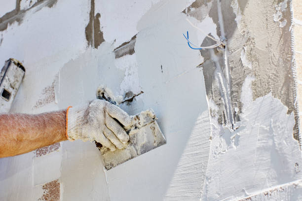 istock Finishing work on cladding of facade of house, construction worker applies cement based adhesive mortar to walls and levels it with steel spatula. 2162606815