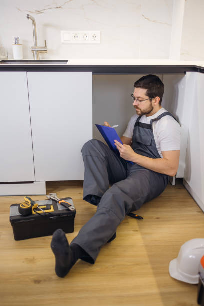 istock Hardworking man in professional uniform entering data in notepad by hand while sitting on parquet of renovated kitchen. 2162607423