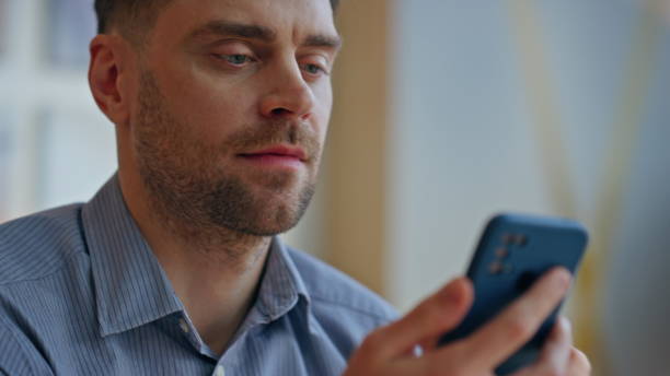 istock Closeup man using smartphone at light room. Happy worker scrolling mobile phone 2162612810