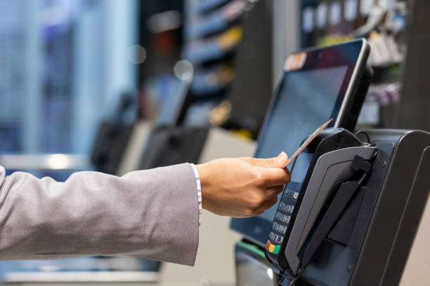 Closeup of hand swiping credit card at payment terminal in retail store Closeup of a person's hand swiping a credit card at a payment terminal in a retail store for a transaction. contactless airport stock pictures, royalty-free photos & images