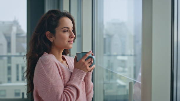 istock Closeup brunette holding coffee mug looking city view from window. Lady thinking 2162616619