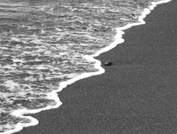 Snapshot of the beach, sand and water with traces of a ball and footsteps where kids were playing ball