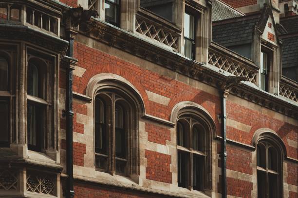 Red brick building with arched windows and intricate stonework in Cambridge, UK.