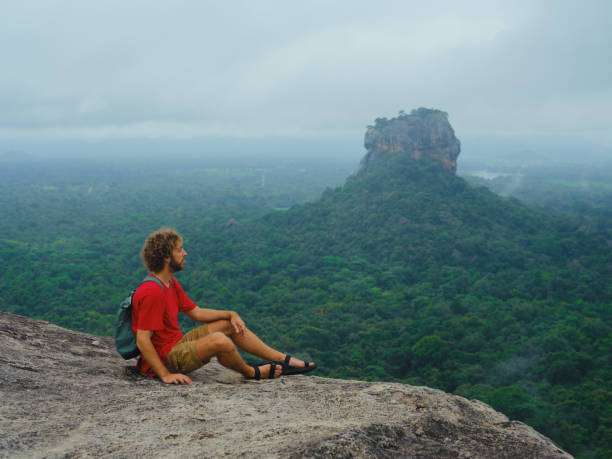 istock Man looking with awe at clouds gathering above Sigiria rock 2162624638