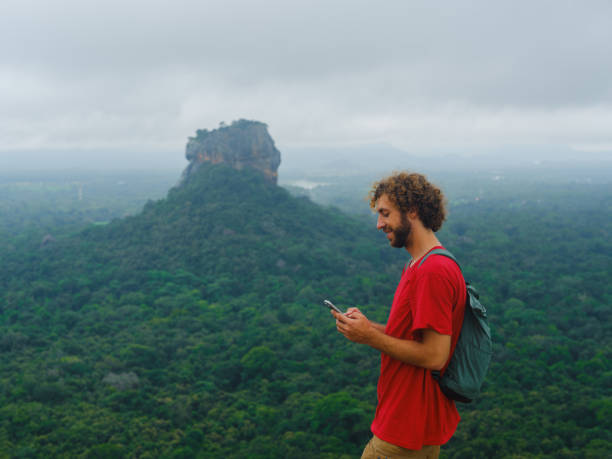 istock Man using smartphone looking at Sigiria rock in Sri Lanka 2162624662