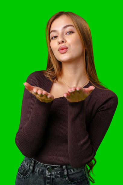 istock Young Woman Blowing a Kiss With Both Hands Against a Green Screen Background 2162625732