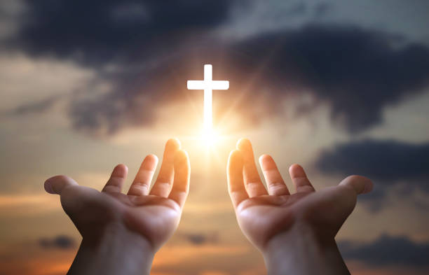 istock Hands holding a cross on sunset sky background. Christian symbol. 2162629017