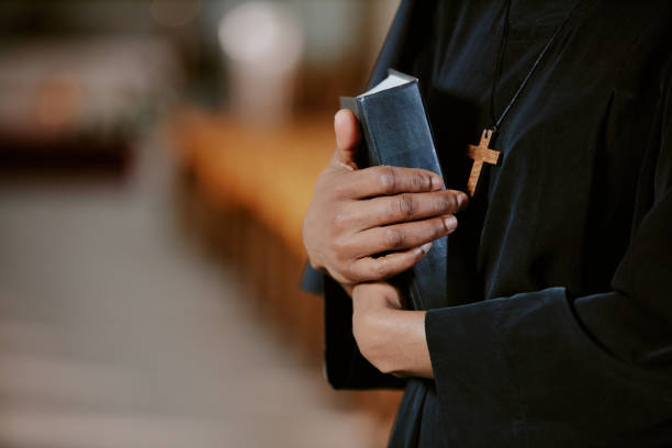 Unrecognizable Black Nun With Book In Hands Closeup of hands of unrecognizable African American nun holding Bible book in hands, copy space nun praying cross human hand stock pictures, royalty-free photos & images