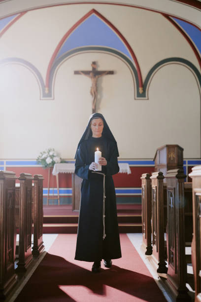istock Senior Nun Walking Along Nave With Candle In Hands 2162630449