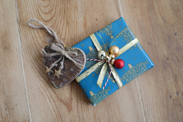 A beautifully wrapped gift with intricate wrapping paper and a decorative bow, placed on a wooden table, close-up. The focus is on the elegant presentation and details of the wrapping.