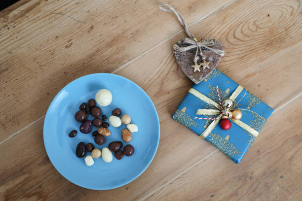 A beautifully wrapped gift with intricate wrapping paper and a decorative bow, placed on a wooden table, close-up. The focus is on the elegant presentation and details of the wrapping.