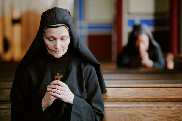 istock Devoted Catholic Nun Praying In Church 2162631484