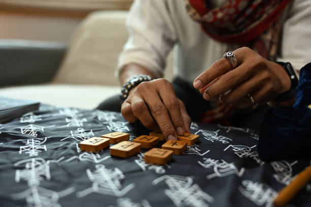 istock Man arranging wooden runes on a table covered with a mystical cloth. Forecasting and divination concept 2162632785