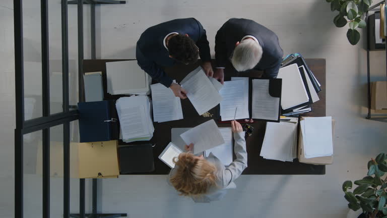 Two Employees and Their Boss Going through Documents in Office