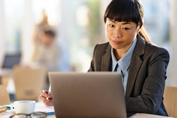 istock Japanese businesswoman taking notes while using laptop in the office. 2162637986