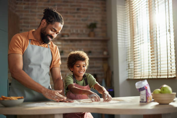 istock Happy black father and son enjoying while making a cake in the kitchen. 2162638010