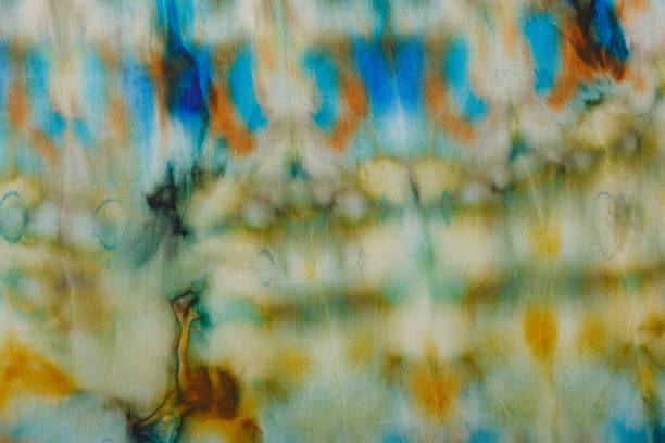 abstract pattern on silk fabric texture in blue, yellow, green colors close up