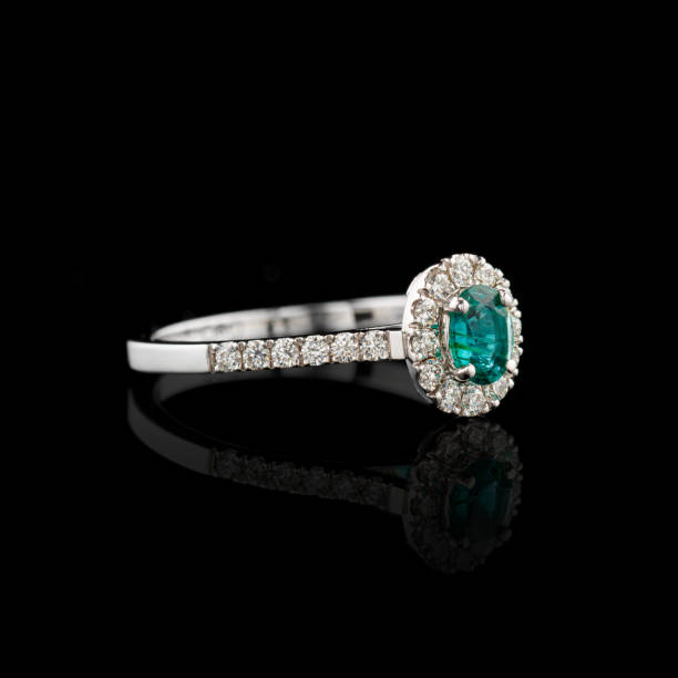 istock Beautiful white gold ring with diamonds and emerald on a black background 2162640077