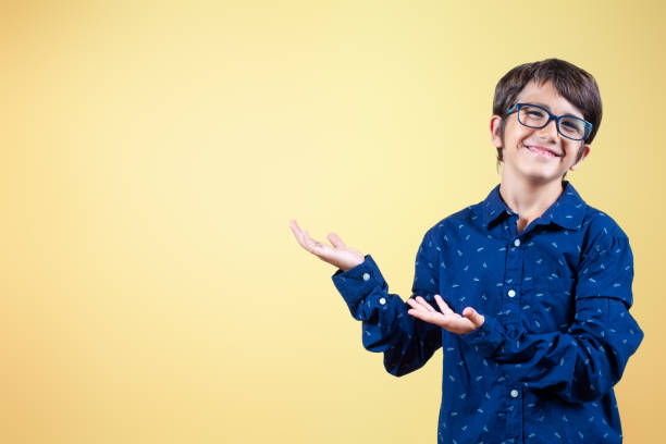 istock Smiling kid with open hands gesturing showing copy space on yellow background. 2162644715