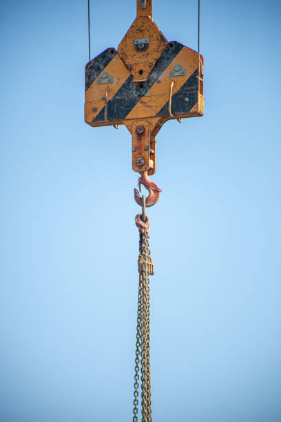 Havana, Cuba - August 7, 2024: Part of a crane on a blue sky. The construction equipment is working in a weathered building wall.