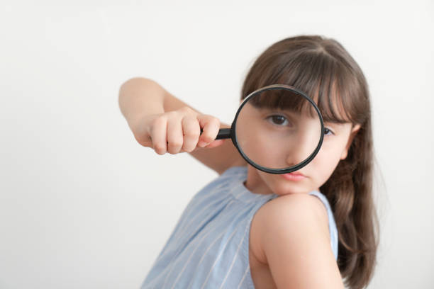 Little girl holding a magnifying glass on a white background