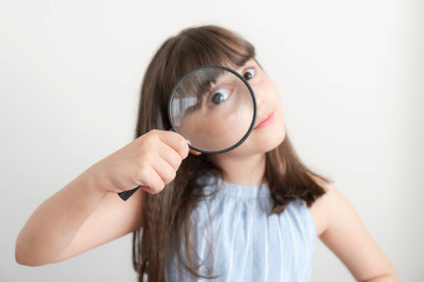 Little girl holding a magnifying glass on a white background